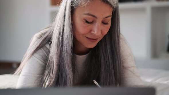 Asian woman working with laptop and writing