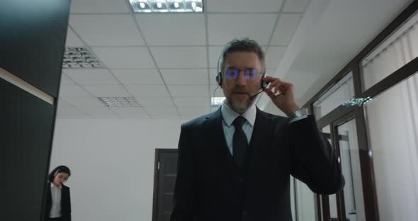 Businessman Phoning with Headset in Office Corridor