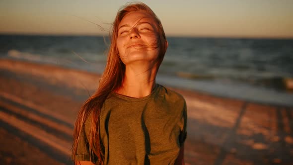 Happy Woman Laughs at Sea on Beach at Sunset