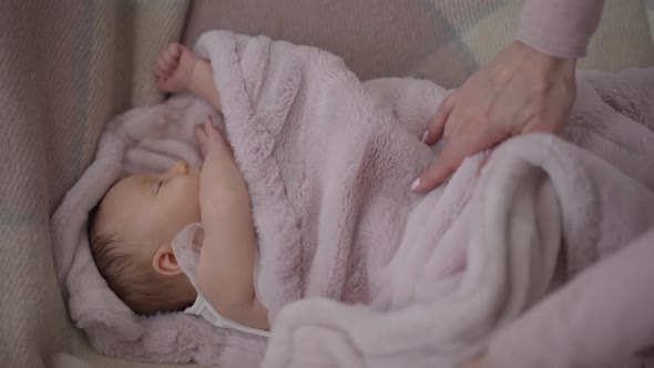 Female Hands Covering Newborn Baby in Slow Motion with Soft Pink Blanket