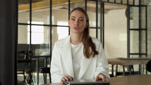 Confident Businesswoman Looking and Talking Through a Webcam During a Video Conference From the