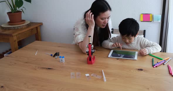 Asian mother at home using tablet with her child for homeworks