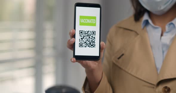 Cropped Shot of Woman in Mask Holding Smartphone with Vaccinated Qr Code for Scanning