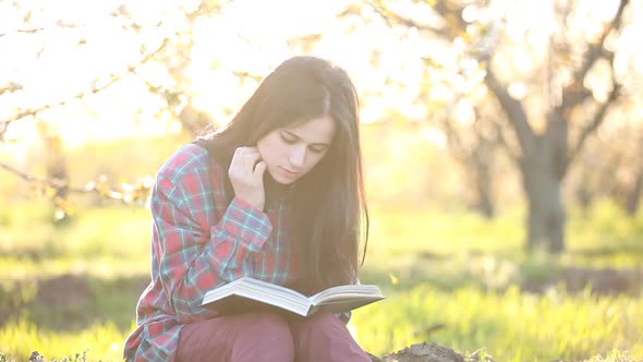 Brunet girl in shirt with notebook at apple tree garden. Spring time