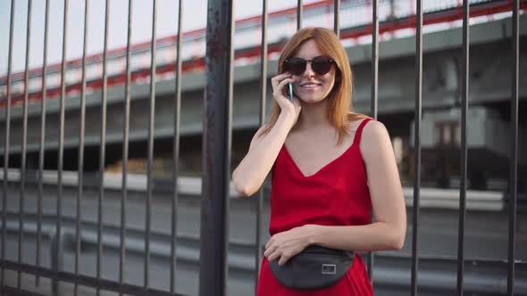 Portrait of Attractive Young Redhaired Woman on Street in Red Dress Use Smartphone