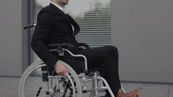 Portrait of Businessman in Wheel Chair Turning Head and Looking To Camera While Standing at Street