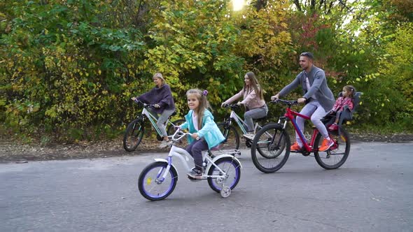 Big family riding bicycles in park in early autumn