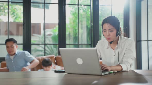 Asian business woman mother talking to colleague team about plan in video conference at home.