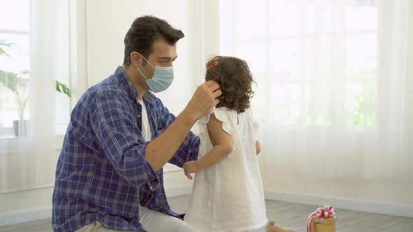 Father is wearing the face mask for little daughter, both are wearing face masks for in their health