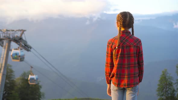 Beautiful Happy Little Girl in Mountains in the Background of Fog