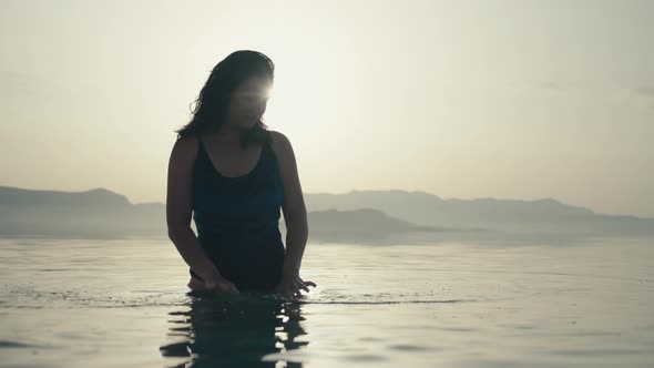 Girl Standing in the Ocean Water at Sunset