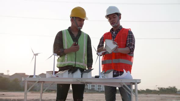 Two Electrical engineers meeting about home solar cell farm and wind turbine model