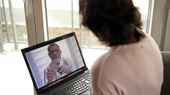 Telemedicine During the Covid-19 Pandemic. Woman Sitting with a Laptop in Her Apartment Consults Her