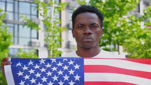 Close Up Afroamerican Man Holding an American Flag and Looks Camera