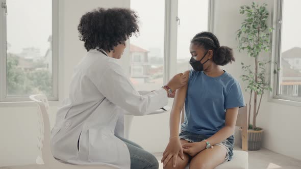 African american doctor is applying plaster to a child's shoulder after being vaccinated. 