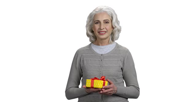 Mature Woman Presenting Gift Box on White Background