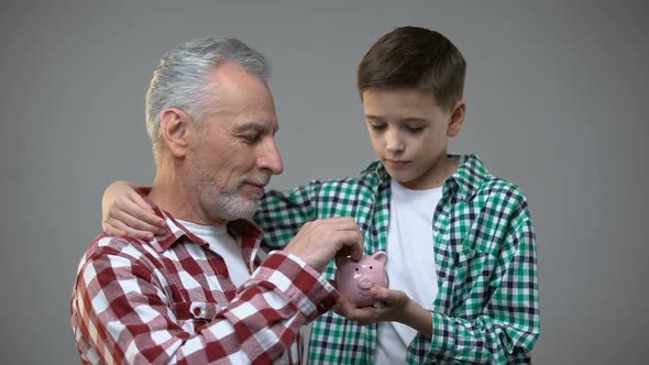 Elderly Man Putting Coin Into Little Boy Piggy Bank, Savings for Future, Banking