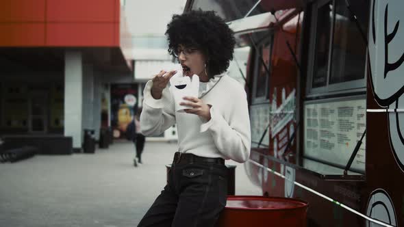 Woman with afro eating outdoors