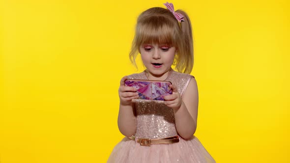 Girl Using Smartphone. Child Texting on Smartphone. Kid Playing Games on Mobile Phone in Studio