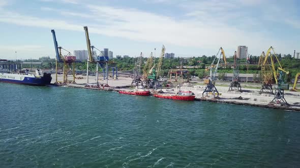 Sea Port Side View. Boats Staying Docks. Crane Loading Ships In Dock.