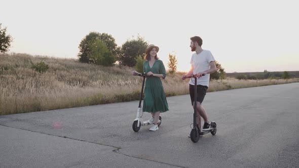 Couple in Love Has a Talk and Holds Hands During a Walk with Electric Scooters