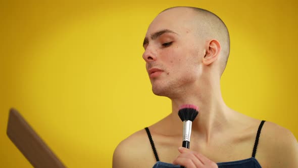 Male Queer Applying Face Powder and Looking at Camera with Confident Facial Expression