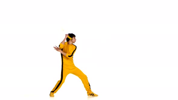 Man in Yellow Suit Training Karate and Expertly Twirling Nunchaku