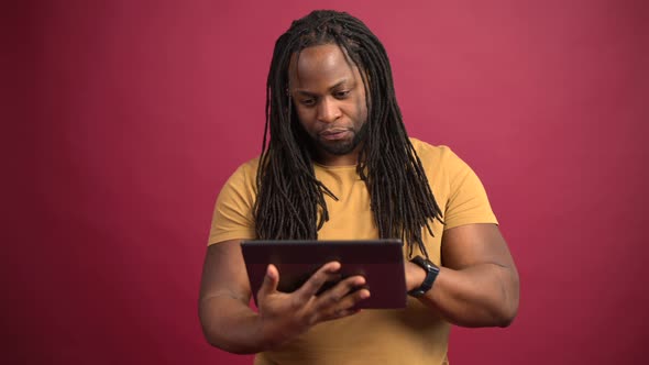 AfricanAmerican Guy Using Tablet Isolated on Red Background