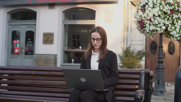 Girl in Glasses and Formal Attire Sitting on Bench Stairs and Typing on Laptop Computer Working