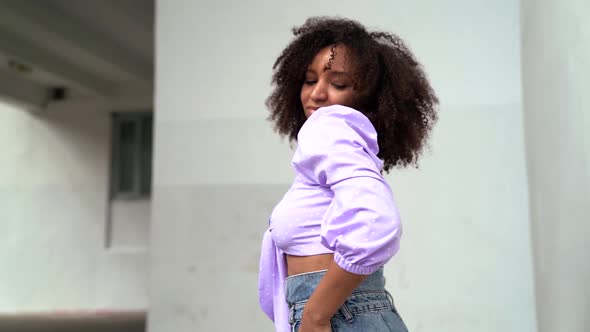 Happy African American Woman Dancing on a City Street Against a Light House Mixed Race Model with