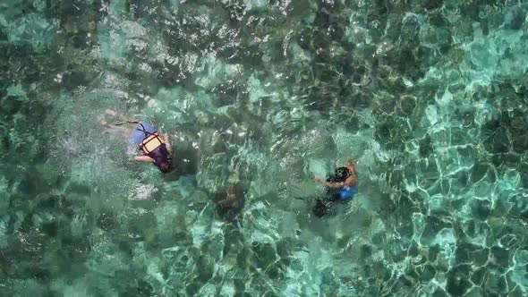Aerial view of two people snorkeling with turtle in Panagsama Beach, Philippines.
