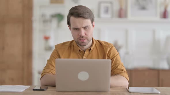 Young Man Reacting to Loss While using Laptop