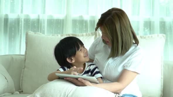 Asian Child And His Mother Using Tablet Together