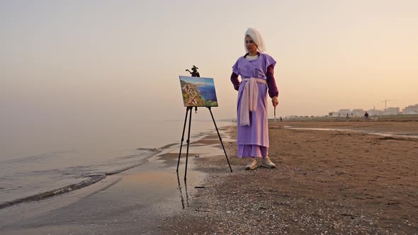 Elegant Woman Looking at Seascape on Easel Put on Sea Beach