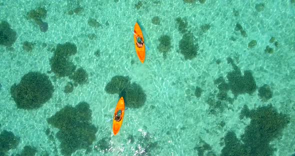 Aerial drone view of a man and woman couple kayaking around a tropical island