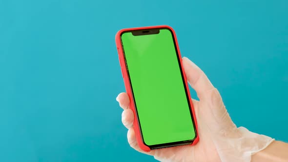 Hand in a Rubber Glove Holds a Smartphone with a Green Screen