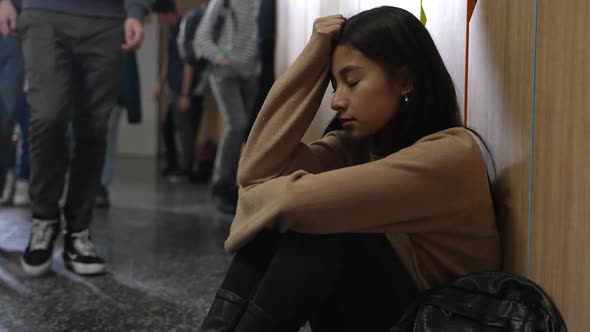 Sad Asian Girl Sitting on Floor By School Locker