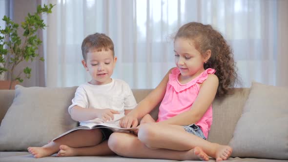 Cute Children,sister with a Younger Brother, Looking at a Book Magazine Textbook Dictionary Tablet