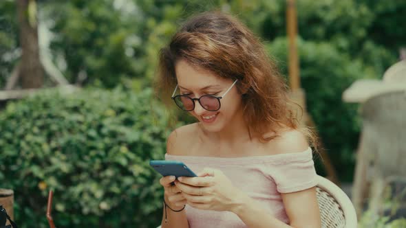 Woman Using Smart Phone in a Restaurant Terrace