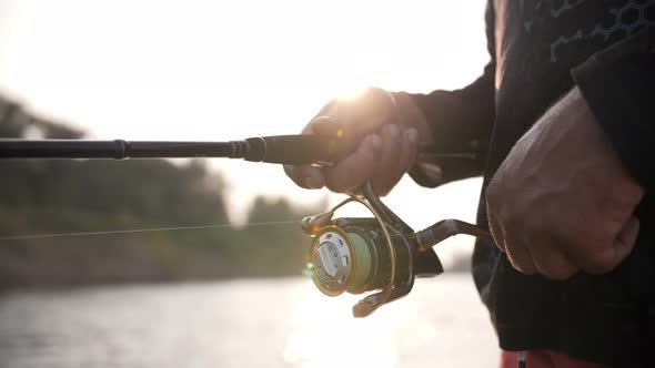 fishing rod in the hands of a fisherman at sunset