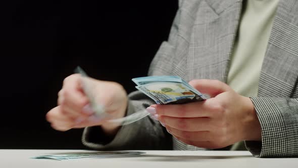 Counting American Hundred Dollar Banknotes on Black Background