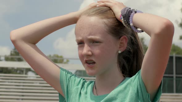 Portrait of a teen girl athlete exhaling and taking a break on the track after a long run