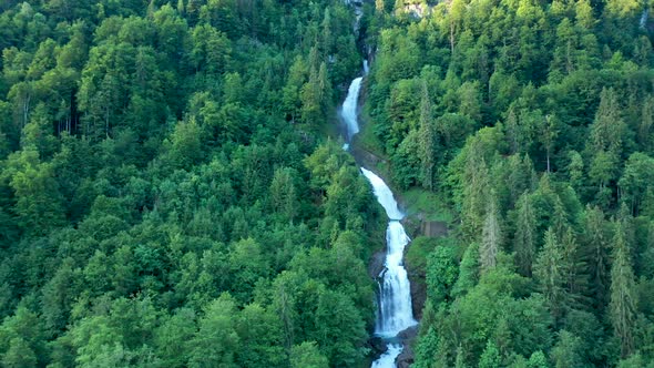 Drone flight over a stunning alpine mountain water fall. The water falls cascade down through the al