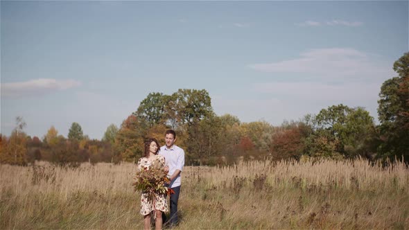 Positive Young Happy Loving Couple. Young Woman Holding Flowers in Hands.