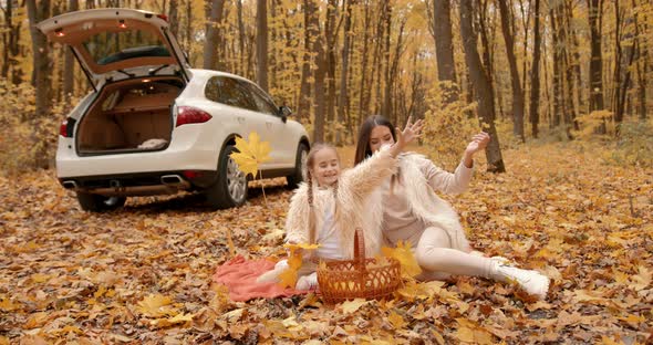 Young Mom and Daughter on a Picnic in Autumn