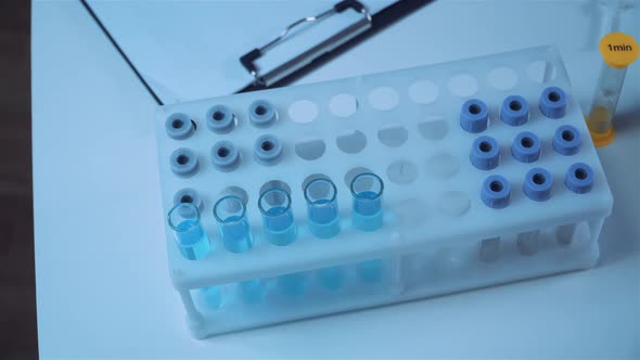 Closeup of Scientists Hand in Blue Latex Gloves Examines Samples Chemical Liquid in Test Tube in