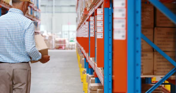 Warehouse worker keeping package in shelf