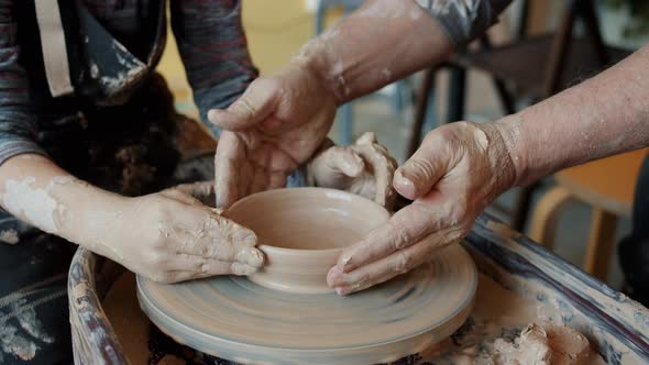 Cinemagraph Loop of Man and Boy's Hands Holding Ceramic Bowl Rotating on Throwing Wheel