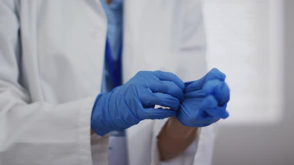 Portrait of mixed race female doctor taking protective gloves off