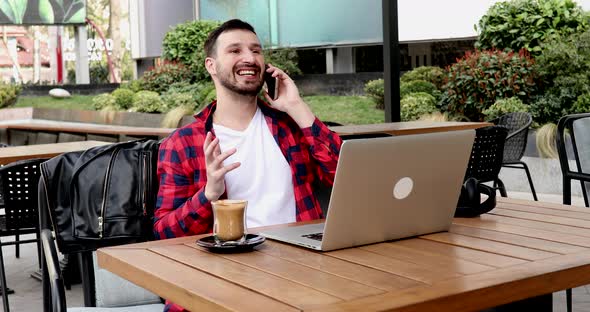 Handsome young businessman using a laptop and a smartphone.